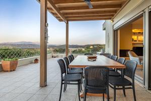 eine Terrasse mit einem Holztisch und Stühlen auf dem Balkon in der Unterkunft Villa Luna, 5 bedrooms, Private Pool, Hot Tub, Garden in Skalánion