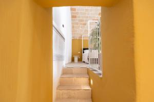 a hallway with stairs and a yellow wall at Acquasale - Antica Dimora Cialledda in Polignano a Mare