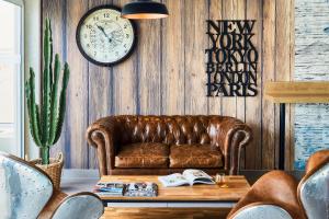 - un salon avec un canapé en cuir brun et une horloge dans l'établissement Ibis Styles Hyères Rooftop & Spa, à Hyères