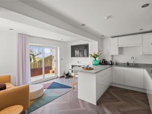 Una cocina con gabinetes blancos y una sala de estar. en Capton Snug, en Dartmouth