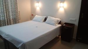 a white bed with two pillows and a night stand at Philips Homestay in Alleppey