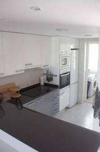 a kitchen with white appliances and a black counter top at Nova Beach Penthouse in Gran Alacant