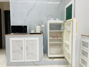 a kitchen with a white refrigerator and a microwave at Mabahj Garnatha Hotel Apartments in Sohar