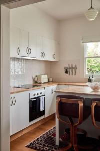 une cuisine avec des armoires blanches, une table et une cuisinière dans l'établissement Mid-Century Modern Retreat, à Kings Park