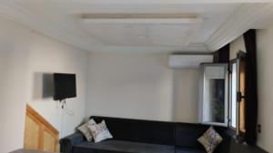 a living room with a black couch and a tv at residence djerba 2 in Houmt Souk