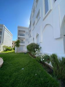 a white building with a green yard with flowers at Luxury sea view apt tanger with Swimming pool in Tangier