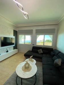 a living room with a black couch and a table at Luxury sea view apt tanger with Swimming pool in Tangier