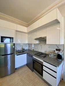 a kitchen with white cabinets and a stainless steel refrigerator at Luxury sea view apt tanger with Swimming pool in Tangier