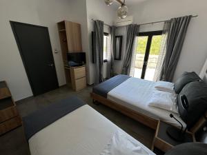 リバディオンにあるBlue Opal House in Livadi Beach Serifosのベッド2台、テレビ、窓のある寝室