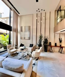 a living room with white furniture and large windows at Studio Terra, Lindo moderno c/ Ar Condicionado in Curitiba