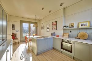 eine Küche mit weißen Schränken und einem Tisch darin in der Unterkunft Captains Cottage in Donaghadee