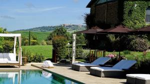 a swimming pool with two chairs and an umbrella at L'Olmo in Monticchiello
