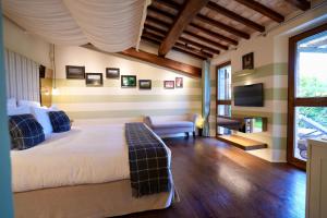 een slaapkamer met een bed, een bank en een tv bij L'Olmo in Monticchiello