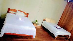 a bedroom with two beds with white sheets at Refugio Chabelita Hostel in Puerto Maldonado