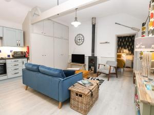 a living room with a blue couch and a kitchen at Cosy Cottage in North Elmham +4 photos