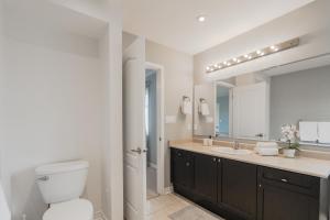 a bathroom with a toilet and a sink and a mirror at Cozy 5 Bedroom House near Toronto Airport in Mississauga +39 photos