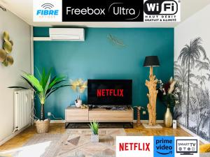 a living room with a tv and a blue wall at L'Oasis -T4 Garage Clim Terrasse WIFI Centre-Ville in Villefranche-sur-Saône