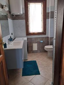 un bagno con lavandino, water e finestra di Comfortable three-room apartment Terza Spiaggia a Golfo Aranci