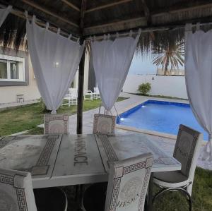 a table and chairs in front of a swimming pool at Ali hot villa in Djerba