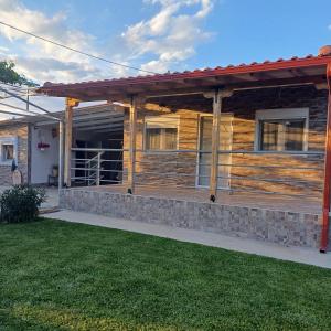 a log home with a porch and grass at Villa Nikos in Nea Plagia