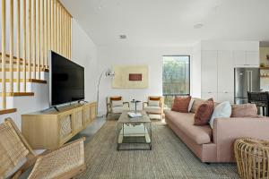 a living room with a couch and a tv at Rooftop Deck, DT City Views, Modern Eastside Oasis in Austin