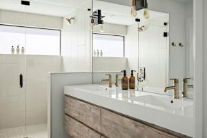 a bathroom with two sinks and a mirror at Rooftop Deck, DT City Views, Modern Eastside Oasis in Austin +51 photos