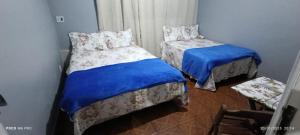a bedroom with two beds with blue sheets at Pousada Pôr do sol in Belém
