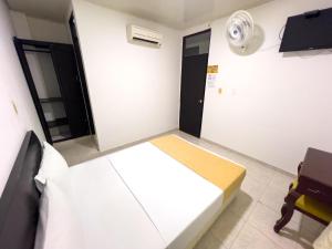 a small room with a bed and a fan at Santa Helena Suite in Acacías
