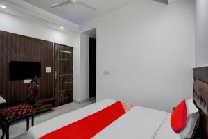a bedroom with a bed and a chair and a tv at Hotel O Elite Signature in Indirapuram +16 photos