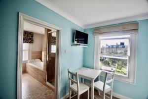 a blue room with a table and chairs and a window at The Art House Hove in Brighton & Hove