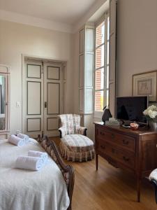 a bedroom with two beds and a tv and a chair at Chambre hôte double 1 in Castelsarrasin