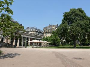 a building with umbrellas in a park with a tree at LOFT Vanelyn RETRO Central Terrace in Wiesbaden