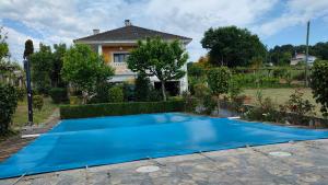 a blue swimming pool in front of a house at Villa con piscina y parque infantil en Pantón, Ribeira Sacra, Galicia in Pantón
