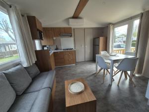 un salon avec un canapé et une table dans l'établissement MOBIL HOME BISCAROSSE LAC - Loc du Samedi au Samedi uniquement, à Biscarrosse 3 autres photos
