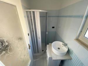 ein weißes Badezimmer mit Waschbecken und Dusche in der Unterkunft Un Tuffo nel Blu in Anzio
