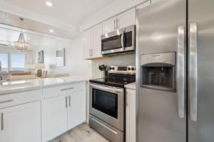 een keuken met witte kasten en een roestvrijstalen koelkast bij HP 24W Condo by 30A Escapes in Rosemary Beach