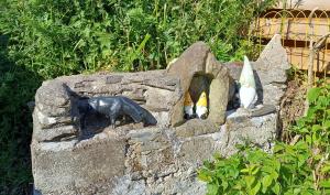 tre gatti che guardano fuori da un muro di pietra di Keriven Cottage a Keriven