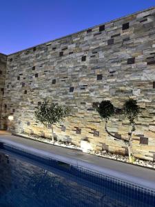 un muro di pietra con tre alberi accanto a una piscina di Bonita casa adosada a Cordoba