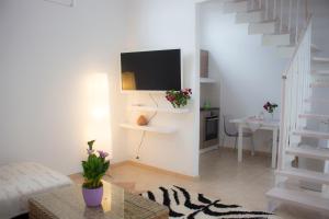 a white living room with a tv and stairs at Cuore dei Monti in Cormòns