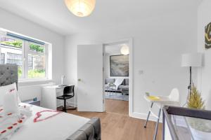a white bedroom with a bed and a living room at The Connected Garden Flat - Parking, Work & Play, 3x in Colindale