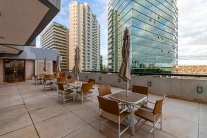 a rooftop patio with tables and chairs and buildings at Ozped Private Flats Manhatan in Brasília