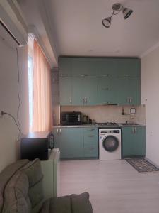 a kitchen with green cabinets and a washing machine at Batumi in Itʼkhvisi