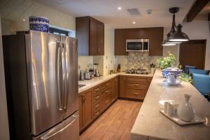 a kitchen with a stainless steel refrigerator and wooden cabinets at 4BD Oceanfront Unit Vista Encantada - Cabo in Cabo San Lucas