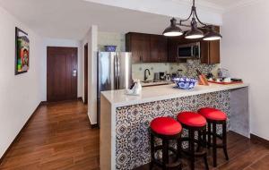 a kitchen with a counter with four red bar stools at 4BD Oceanfront Unit Vista Encantada - Cabo in Cabo San Lucas +38 photos