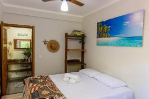 a bedroom with a bed and a picture of the ocean at Casa a 3 min andando da Praia de Paúba com WIFI top in São Sebastião +66 photos