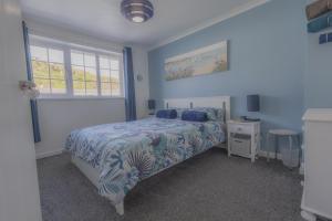 una camera da letto blu con un letto e una finestra di Inner Harbour Cottage a Portreath