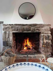 ein Kamin mit einem Feuer darin und einem Spiegel in der Unterkunft House in the Mountains of Toledo in San Pablo de los Montes