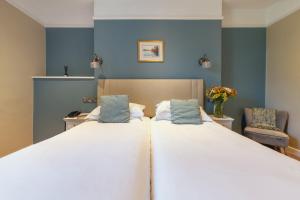 a bedroom with a large white bed with blue walls at Stoke Lodge Hotel in Stoke Fleming