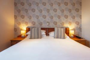 a bedroom with a large white bed with two lamps at Stoke Lodge Hotel in Stoke Fleming