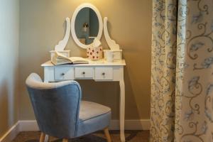 a dressing table with a chair and a mirror at Stoke Lodge Hotel in Stoke Fleming